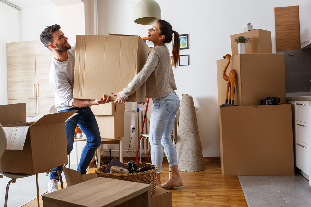 Young couple carrying big cardboard box at new home.Moving house.