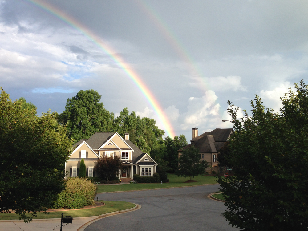 A rainbow is seen over a suburban Atlanta two-story house in the best suburbs in Atlanta.
