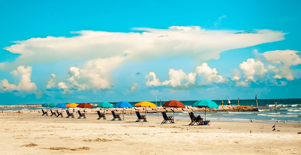 A row of colorful beach umbrellas and beach loungers on Galveston Island Texas.