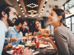 A group of friends laughing in a restaurant having made friends as digital nomads.