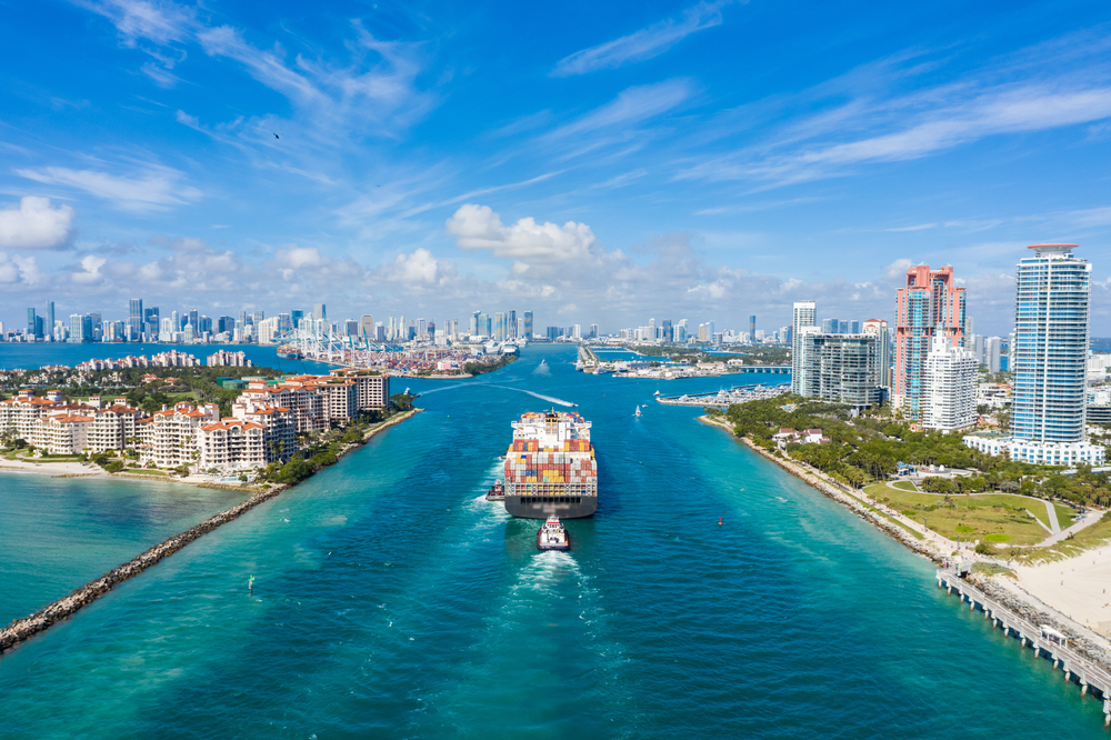 Large Container Ship Entering Harbor and Miami City on Sunny Day, USA. Aerial View. Large Container Ship Entering Harbor and Miami City on Sunny Day, USA. Aerial View.