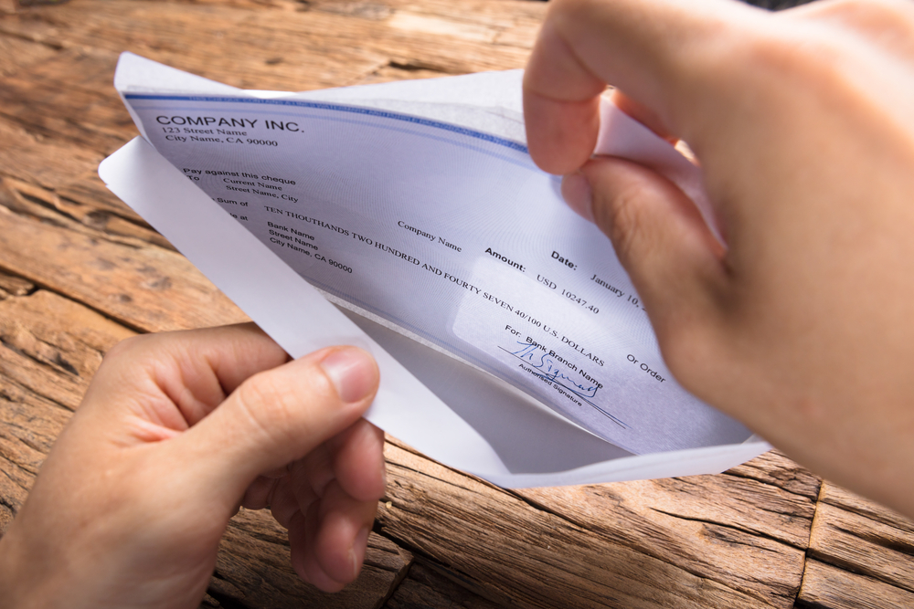 Cropped hands of businessman opening envelope with paycheck