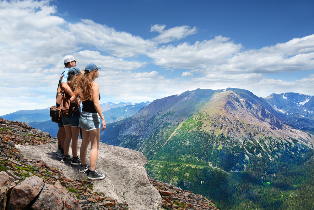 Group of people looking at summer mountains landscape, on hiking trip, on top of mountain. View from Trail Ridge Road. Estes Park, Rocky Mountains National Park, Colorado. 