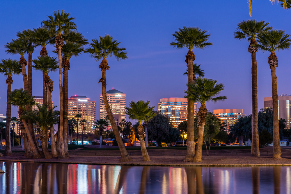 The lights of downtown Phoenix office buildings are reflected in the waters of the Encanto Park lagoon.