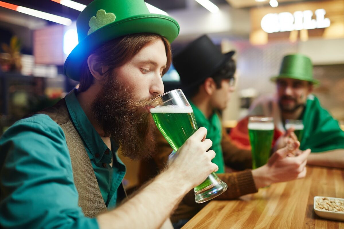 Man drinks green beer at a bar on St. Patrick's Day.
