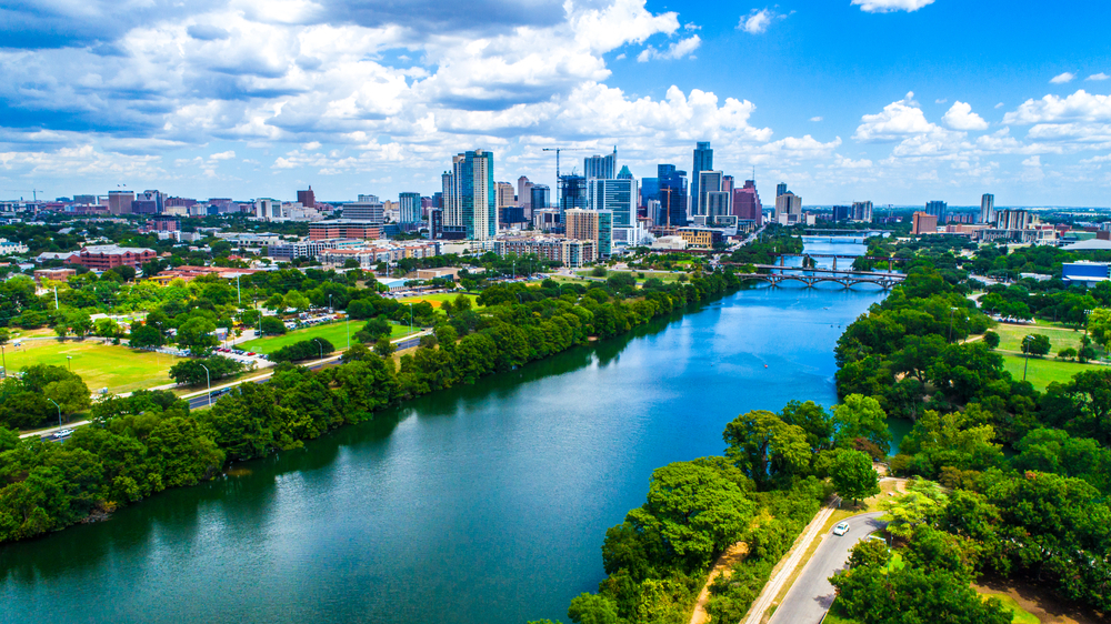 Aerial drone view above Lady Bird Lake in Austin Texas with city skyline in background on a wonderful summer day blue sky green landscape and fresh cold spring swimming hole water
