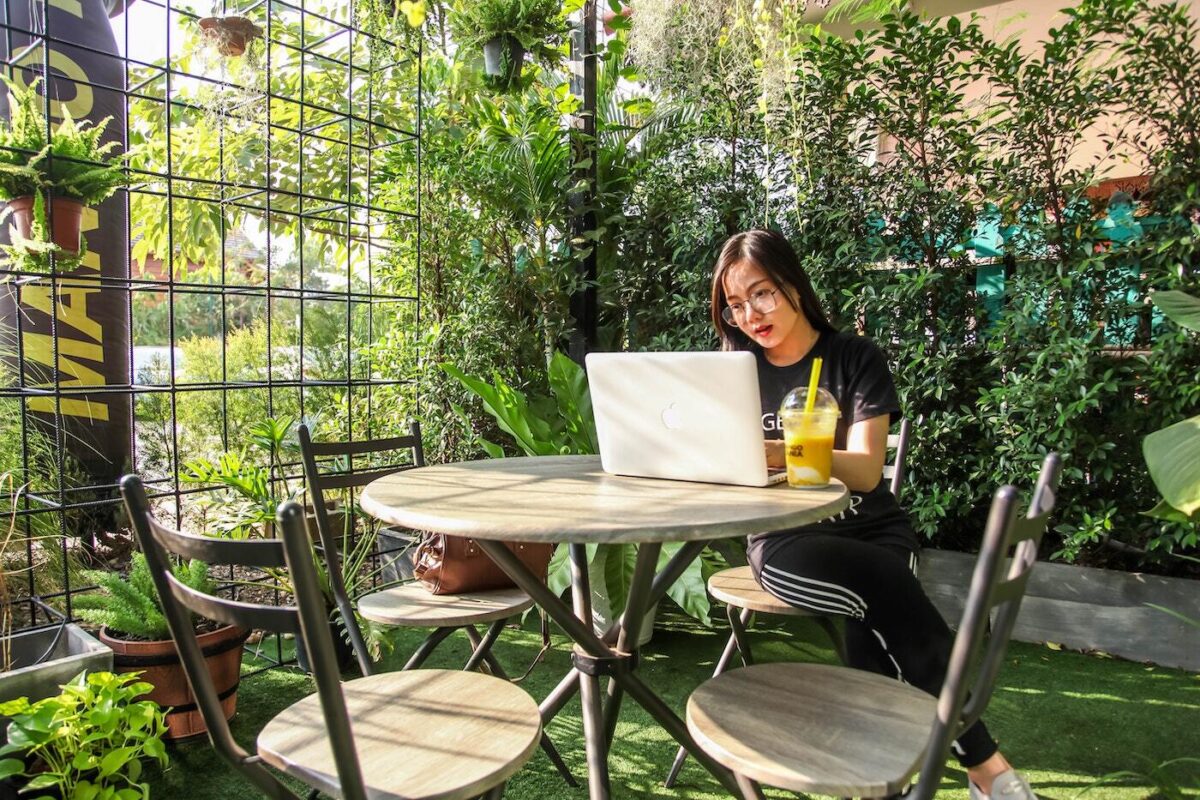 Digital nomad works from a plant-filled cafe.