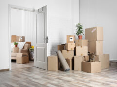A view through a doorway of two rooms with large piles of cardboard boxes.