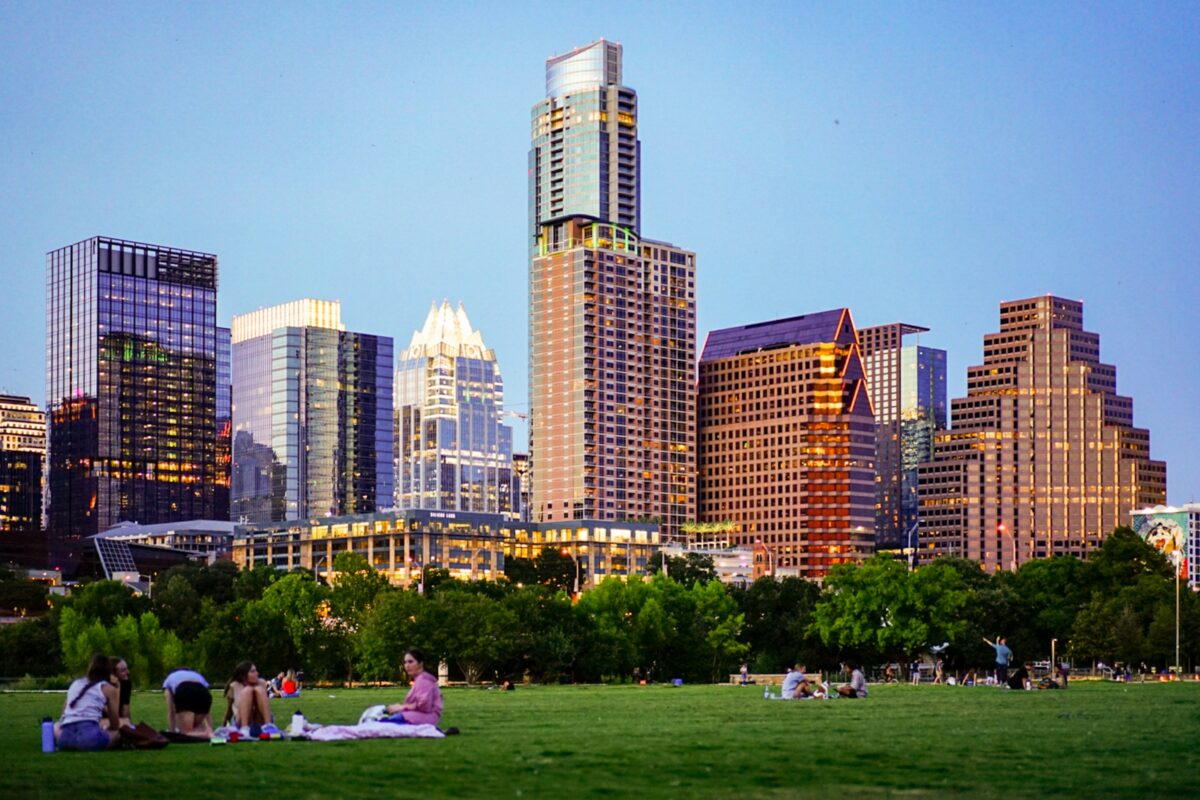 People enjoying a sunny day having picnics at the park with Austin's city in the background