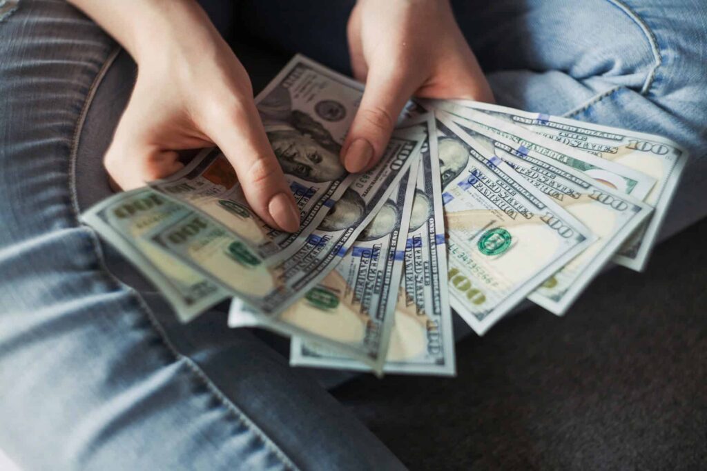 Two hands holding a stack of 100 dollar bills