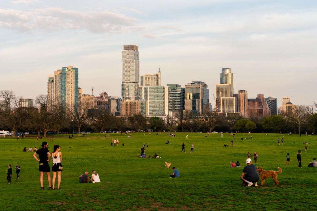 People enjoying a day out at Zilker Park. In the background, Austin's buildings arise. 