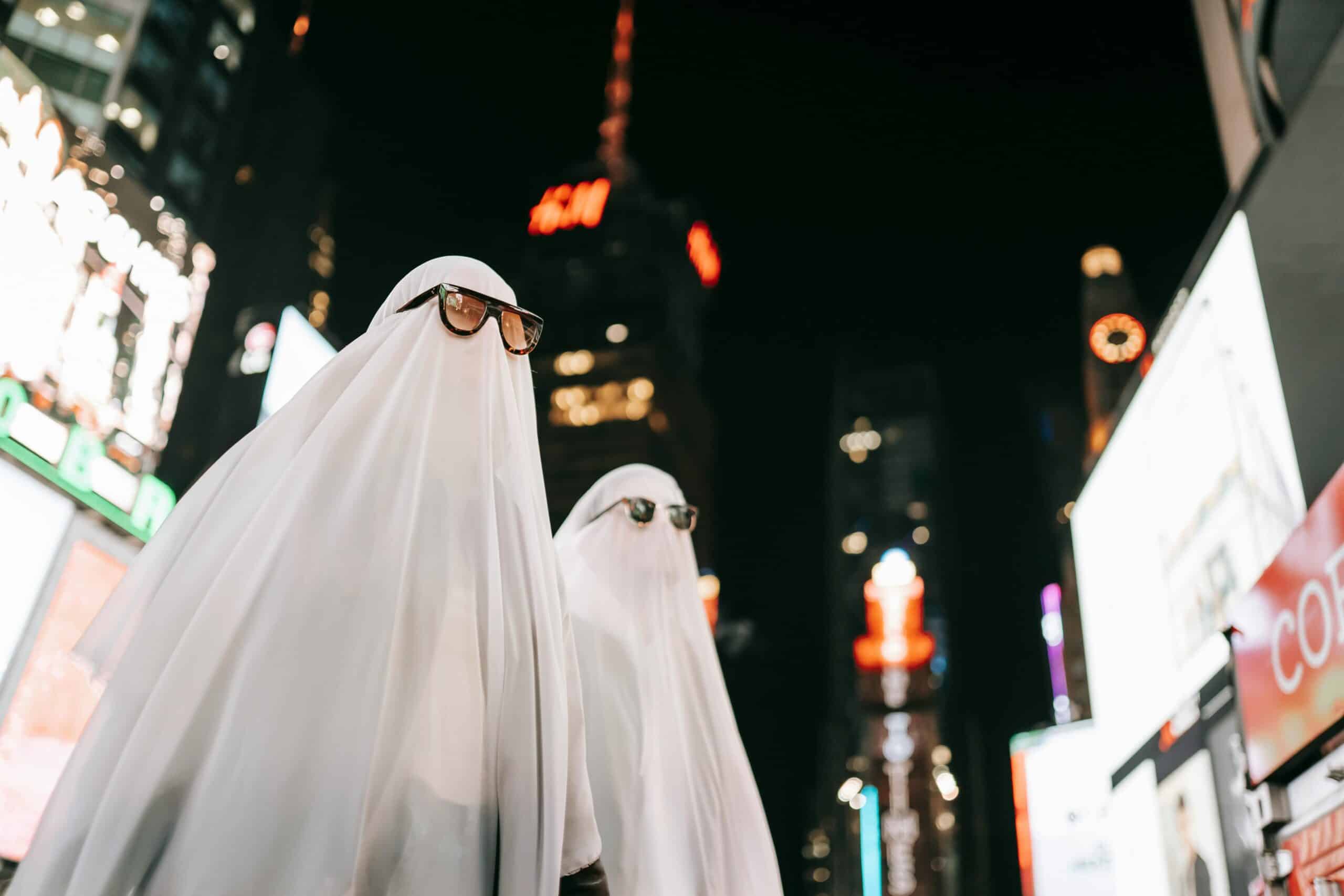 Couple in ghost costumes in a city during Halloween