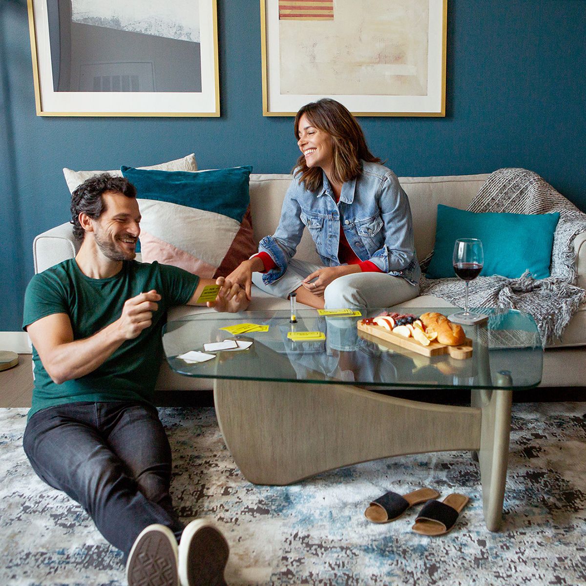 Couple relaxing with snacks and a card game in their furnished apartment after a move