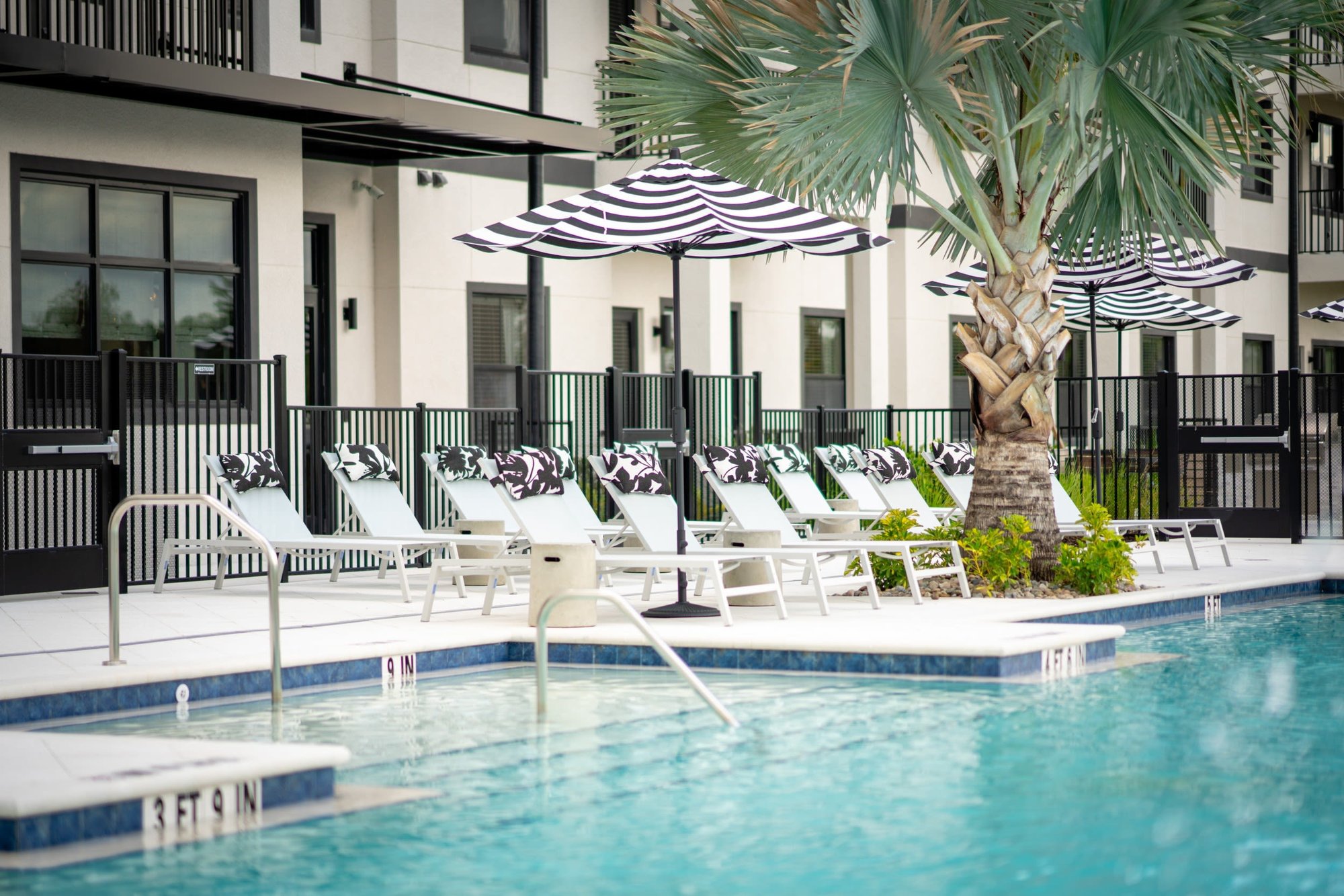 Pool with striped umbrellas and lounge chairs at Evergreen Pine Island in Cape Coral, Florida