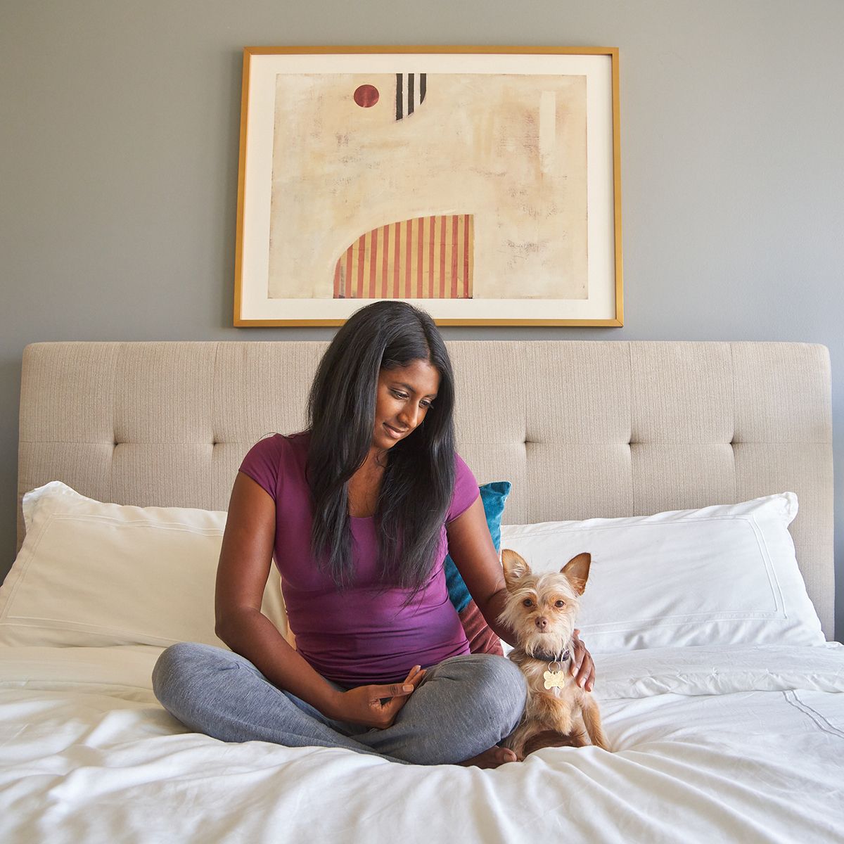 Woman sitting on a bed with her dog in a pet-friendly furnished apartment